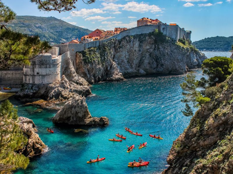 Blick auf die Stadtmauer von Dubrovnik und eine Gruppe von Seglern.