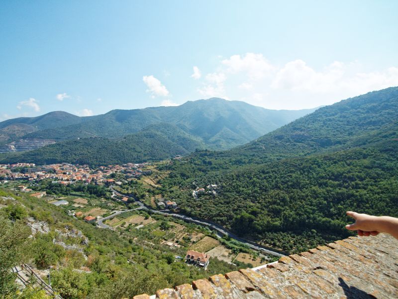 Ausblick auf die Hügel Liguriens, mit einem kleinen Dorf inmitten bewaldeter Hügel