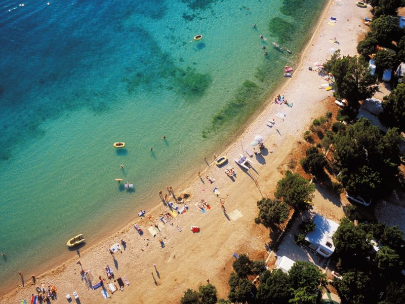 Campingplatz am Sandstrand in Kroatien mit klarem türkisblauem Wasser