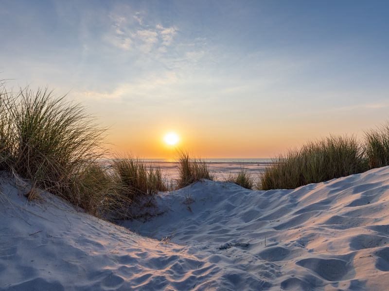 Sonnenuntergang über den Dünen am Strand in Holland