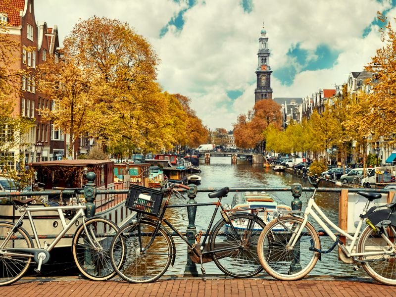 Gracht in Amsterdam, mit Fahrrädern im Vordergrund und alten Häusern im Hintergrunf