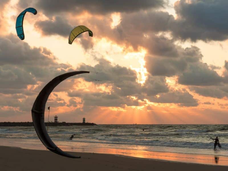 Kitesurfer bei untergehender Sonne am Strand