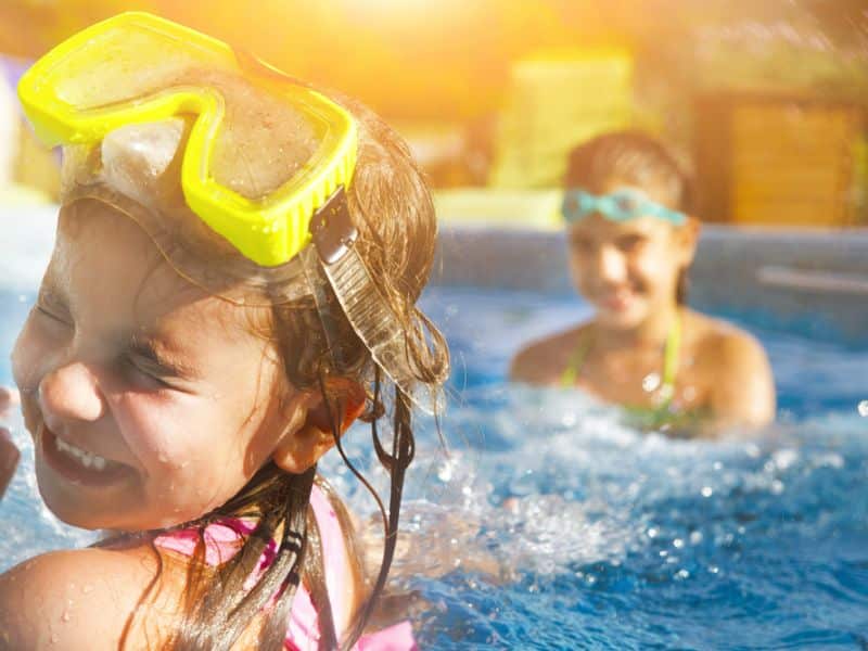 Zwei Kinder beim plantschen im Wasser mit großer Schwimmbrille