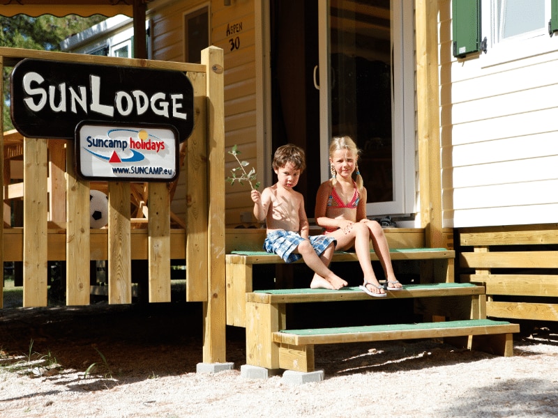 SunLodge Aspen mit einem Jungen und einem Mädchen, die auf den Stufen der Veranda sitzen