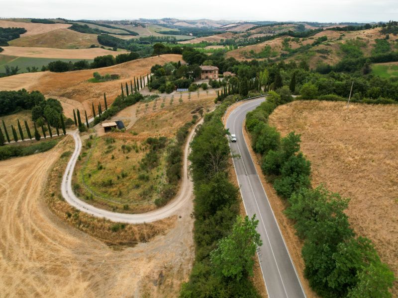 Weißes Auto auf einer kurvigen Landstraße in Italien