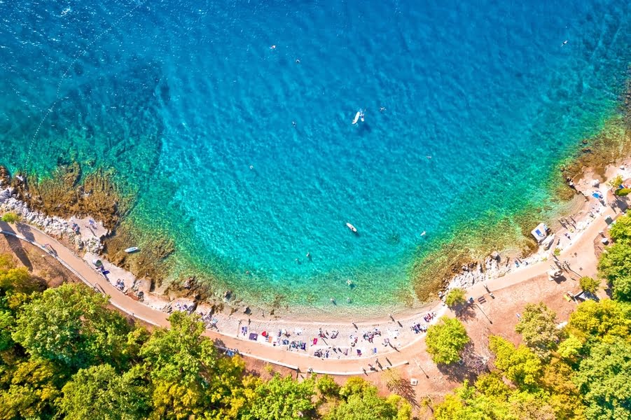 Luftaufnahme eines weißen Strandes mit klarem blauem Meer