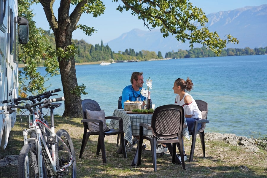 Paar sitzt bei Camper am Meer
