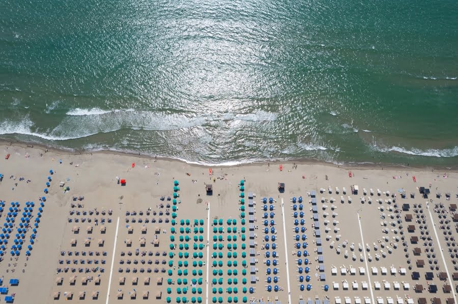 Luftaufnahme eines Strandes mit Liegen und Sonnenschirmen