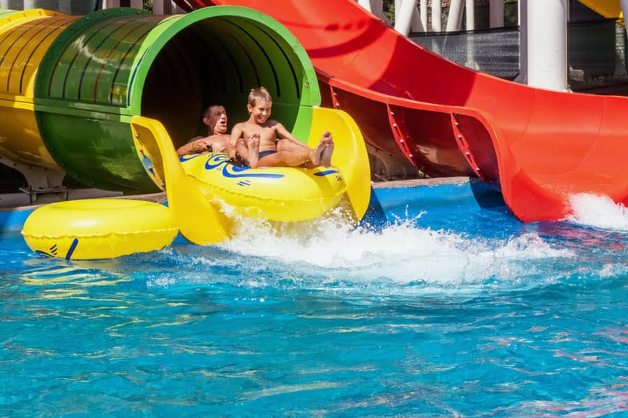Vater und Sohn rutschen in einem Reifen eine Wasserrutsche hinunter